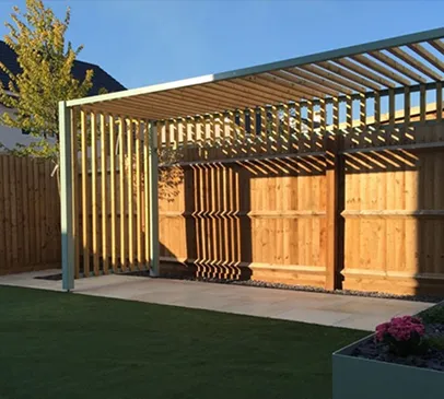 Pergola moderne en bois avec des ombres marquées sur une clôture et du gazon à Croissy-sur-Seine dans les Yvelines 78