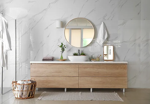 Salle de bain moderne blanche avec carrelage marbré, vanité en bois, lavabo et miroir rond à Croissy-sur-Seine dans les Yvelines 78