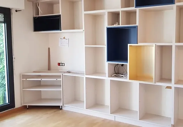 Bibliothèque modulaire en bois clair avec étagères bleues et dorées, en cours d'installation à Croissy-sur-Seine dans les Yvelines 78